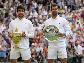 L'Espagnol Carlos Alcaraz, à gauche, célèbre avec le trophée après avoir battu le Serbe Novak Djokovic, à droite, pour remporter la finale du simple masculin lors de la quatorzième journée des championnats de tennis de Wimbledon à Londres, dimanche 16 juillet 2023.