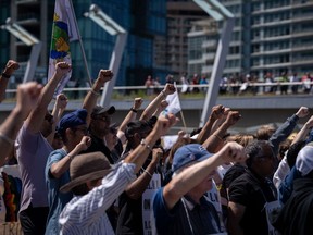 Des travailleurs portuaires en grève de l'International Longshore and Warehouse Union Canada lèvent le poing lors d'un rassemblement à Vancouver, le dimanche 9 juillet 2023.