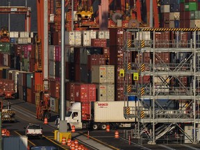 L'organisation qui emploie des travailleurs portuaires à travers la Colombie-Britannique affirme que des milliers d'employés sont en grève à partir d'aujourd'hui.  Un camion transporte un conteneur de fret au terminal à conteneurs du port de Vancouver Centerm alors que d'autres sont empilés sous des grues à portique, à Vancouver, le vendredi 14 octobre 2022.