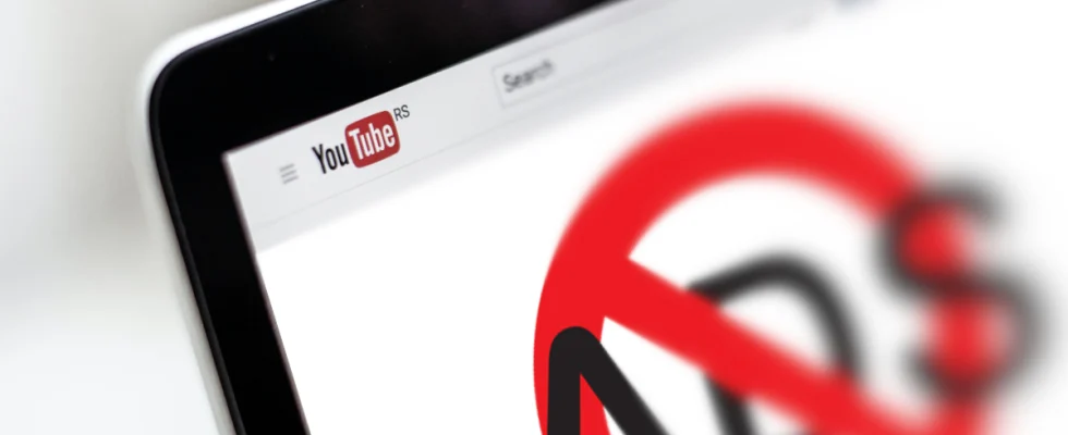 YouTube on a laptop screen with a big "no ads" logo in the middle.