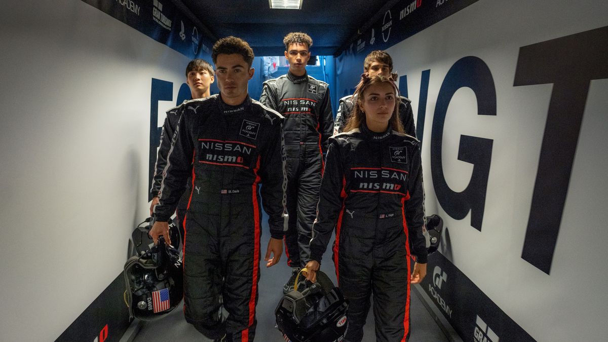 Une équipe de jeunes coureurs en salopette marche dans un couloir dans le film Gran Turismo