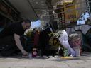 Une femme allume une bougie, à l'endroit où un fan grec de 29 ans est décédé après des affrontements nocturnes entre supporters rivaux dans la banlieue de Nea Philadelphia, à Athènes, en Grèce, le mardi 8 août 2023.  