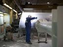 Un travailleur enduit de poudre un poteau à l'usine d'Automatic Coating Ltd. à Toronto.