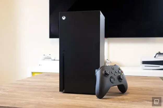 Image de la Xbox One Series X sur une table en bois de hêtre devant un téléviseur grand écran.
