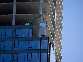 Des ouvriers installent des pans de murs préfabriqués dans un condo en construction à Montréal.