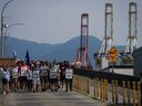 Les travailleurs en grève de l'International Longshore and Warehouse Union Canada marchent vers un rassemblement alors que les grues à portique utilisées pour charger et décharger les conteneurs de fret des navires sont inactives au port de Vancouver le jeudi 6 juillet 2023.