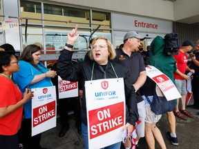 Lana Payne, présidente nationale d'Unifor, crie aux côtés des travailleurs sur une ligne de piquetage devant une épicerie Metro à Toronto.