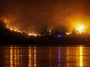 Le feu de forêt de McDougall Creek brûle à flanc de montagne au-dessus des maisons au bord du lac, à West Kelowna, en Colombie-Britannique, le vendredi 18 août 2023.