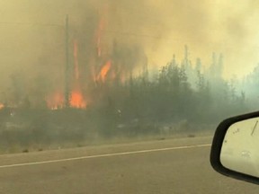 Véhicules roulant dans la fumée sur l'autoroute alors que les gens évacuent Yellowknife
