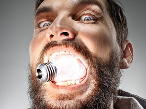 Homme de race blanche avec ampoule dans sa bouche sur fond gris