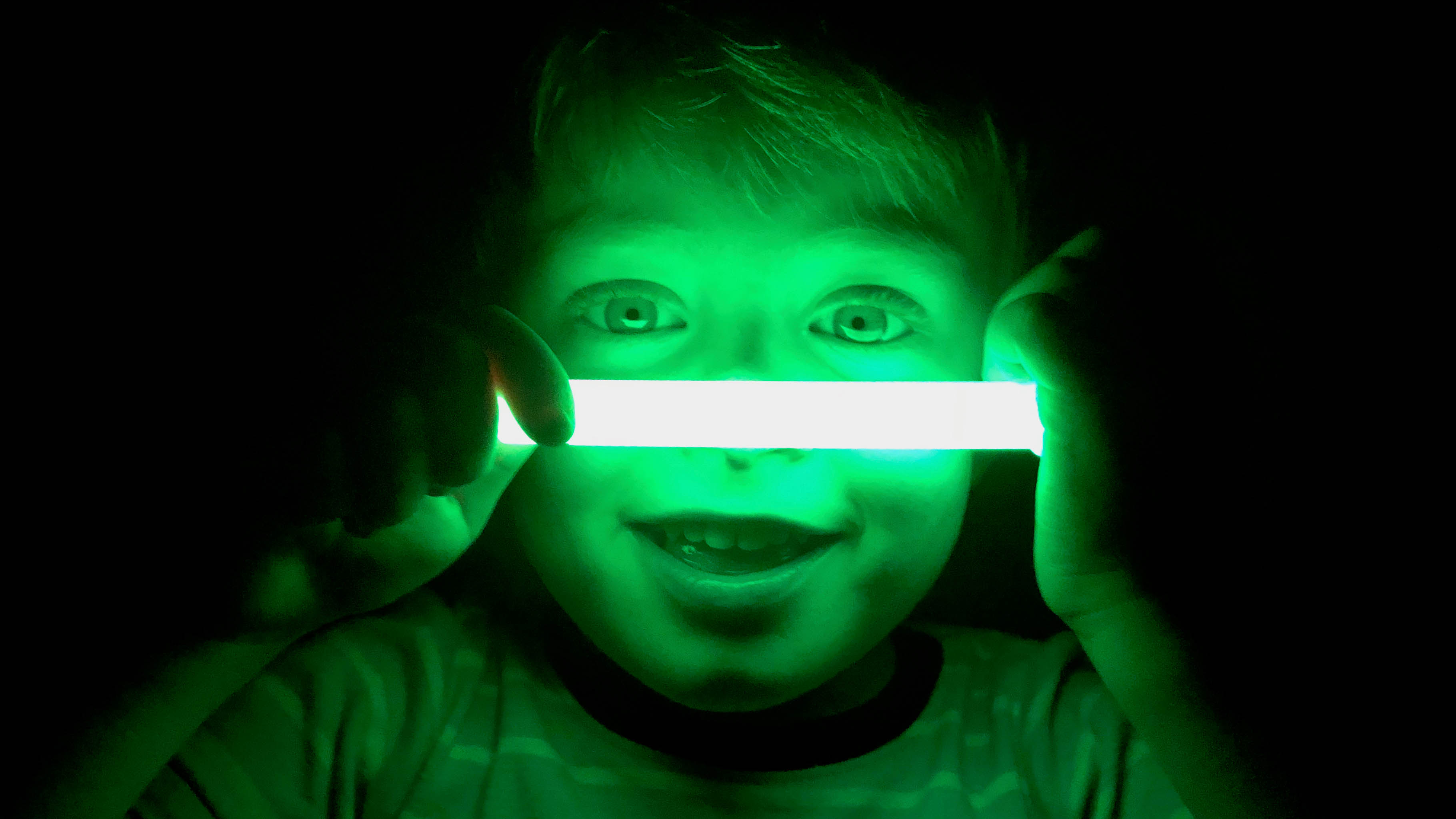 Jeune enfant tenant un bâton lumineux vert jusqu'à son visage