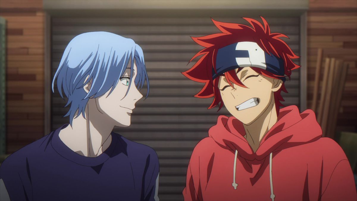 Un garçon anime aux cheveux bleus se tient à côté d’un garçon anime souriant aux cheveux roux.