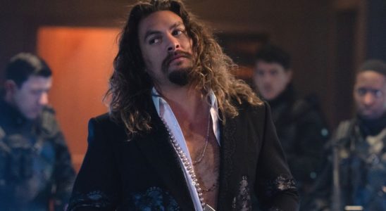 Jason Momoa stands in front of some armed guards with his head cocked to the side in Fast X.