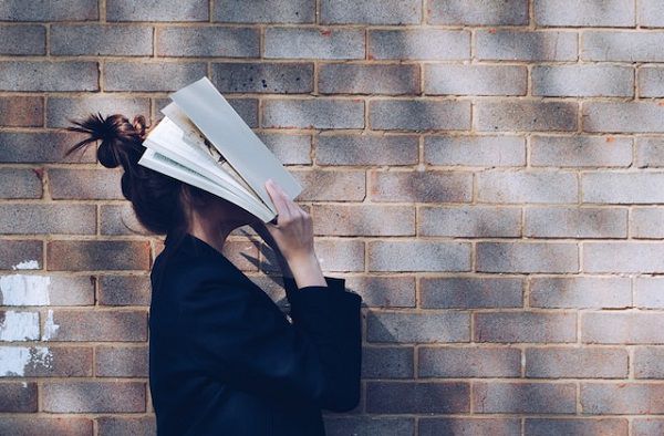 une photo d'une personne tenant un livre sur son visage