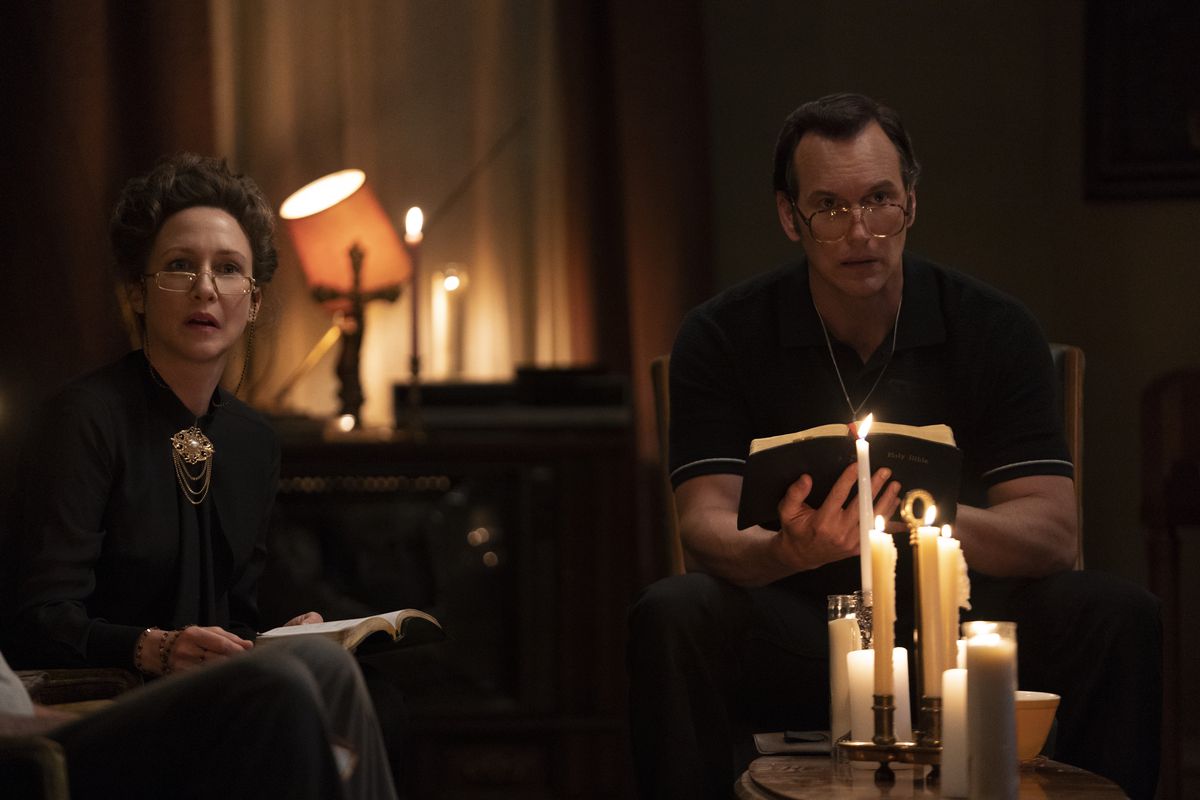Ed et Lorraine Warren sont assis avec des bibles à la lumière des bougies dans The Conjuring: The Devil Made Me Do It