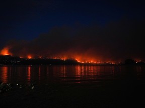 Le feu de forêt de McDougall Creek brûle à flanc de montagne au-dessus des maisons au bord du lac à West Kelowna, en Colombie-Britannique, le vendredi 18 août 2023.