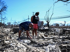 Davilynn Severson et Hano Ganer recherchent des effets personnels dans les cendres de la maison de leur famille à la suite d'un incendie de forêt à Lahaina, dans l'ouest de Maui, à Hawaï, le 11 août 2023.