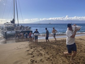 Un groupe de bénévoles qui ont navigué depuis Maalaea Bay, Maui, forment une chaîne de montage sur la plage de Kaanapali le samedi 12 août 2023, pour décharger les dons d'un bateau.  Les habitants de Maui se sont réunis pour donner de l'eau, de la nourriture et d'autres fournitures essentielles aux habitants de l'ouest de l'île après qu'un incendie meurtrier a détruit des centaines de maisons et laissé des dizaines de personnes sans abri.