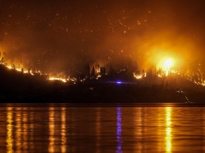 Le feu de forêt de McDougall Creek brûle à flanc de montagne au-dessus des maisons au bord du lac, à West Kelowna, en Colombie-Britannique, le vendredi 18 août 2023.