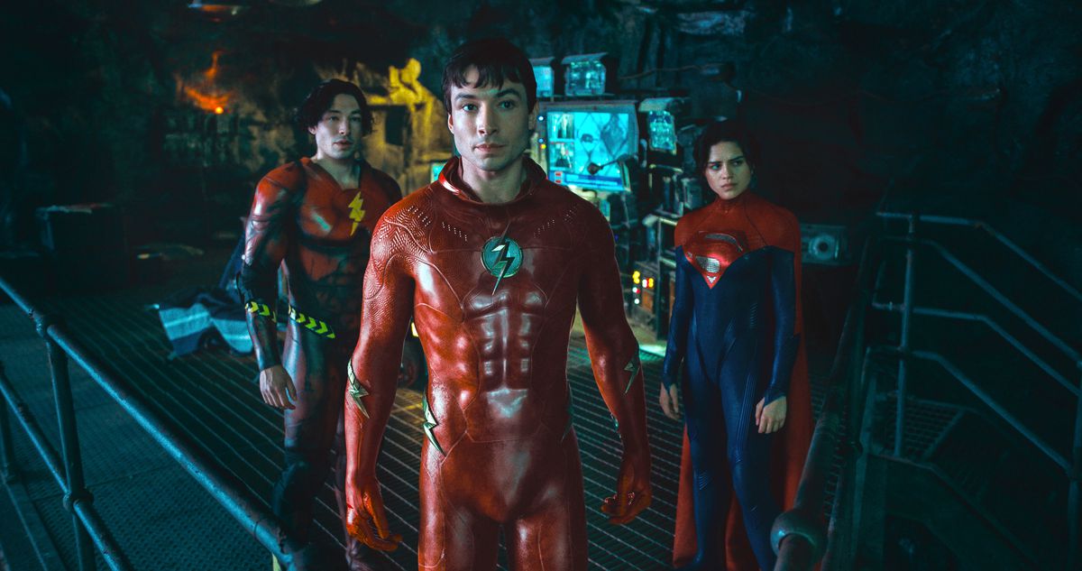 (De gauche à droite) Ezra Miller dans le rôle de Young Barry, Ezra Miller dans le rôle de Barry/The Flash et Sasha Calle dans le rôle de Supergirl debout dans la Batcave dans leurs costumes dans The Flash.