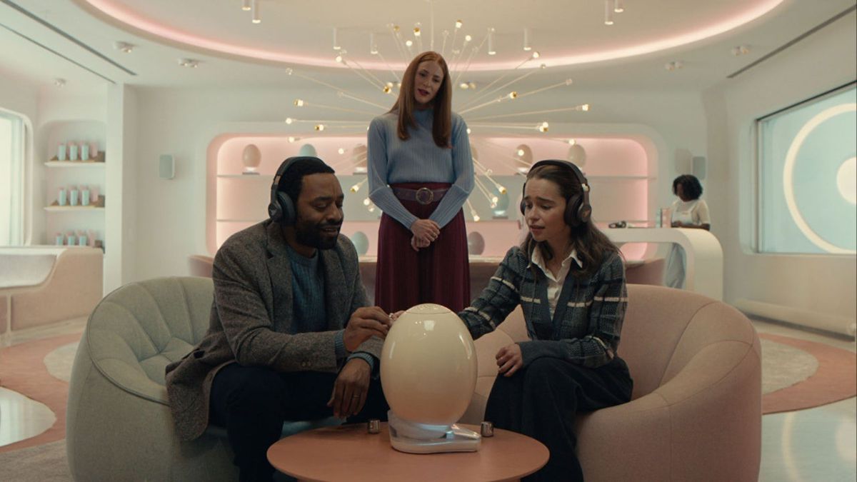 (De gauche à droite) Chiwetel Ejiofor, Rosalie Craig et Emilia Clarke assises autour d'un petit appareil en forme d'œuf dans The Pod Generation.