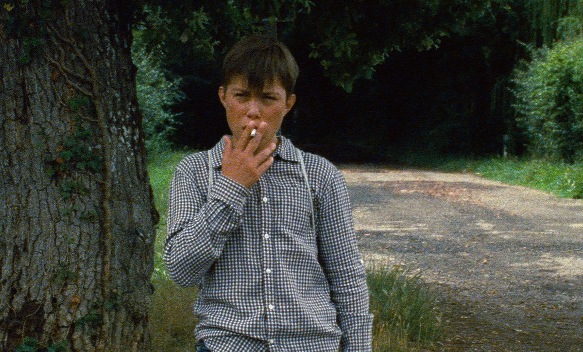 Un très jeune garçon fume une cigarette sur une image granuleuse d'Astrakan