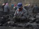 Cette photo d'archive prise le 20 novembre 2015 montre un ouvrier triant du charbon sur un tapis roulant, près d'une mine de charbon à Datong, dans la province du Shanxi, dans le nord de la Chine.