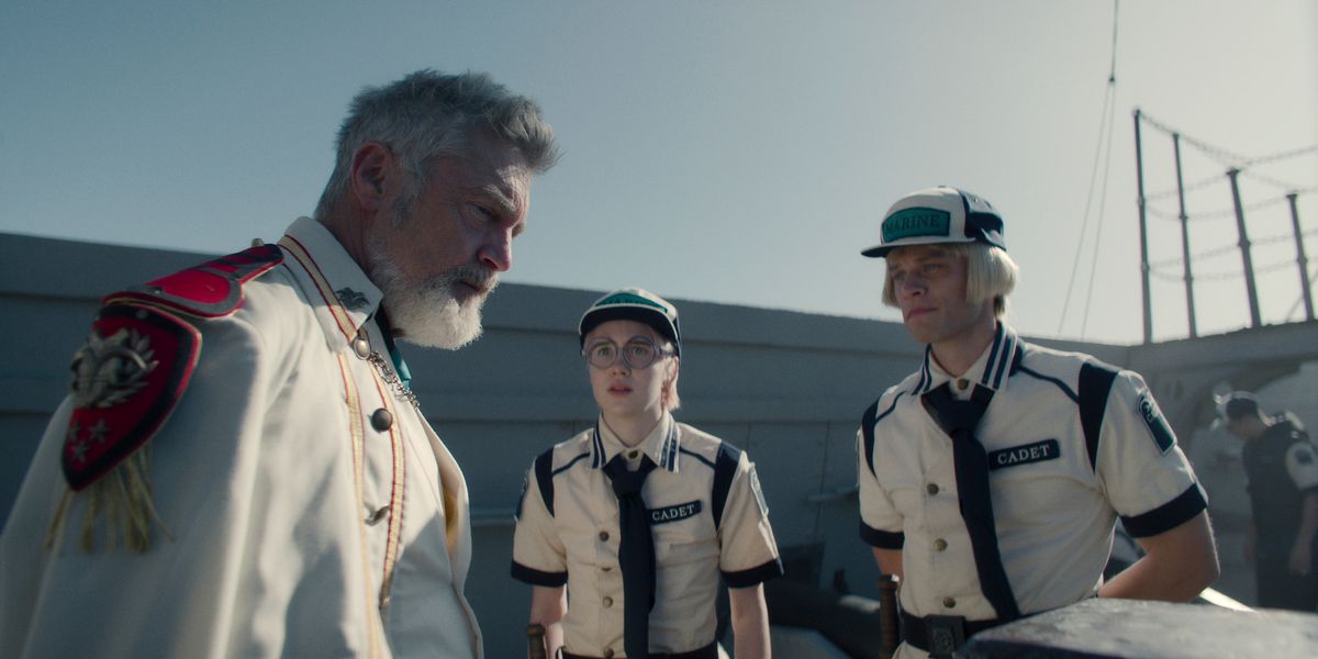 Vincent Regan dans le rôle du vice-amiral Garp, Morgan Davies dans le rôle de Koby et Aidan Scott dans le rôle d'Helmeppo, debout et parlant sur le pont d'un navire de la marine