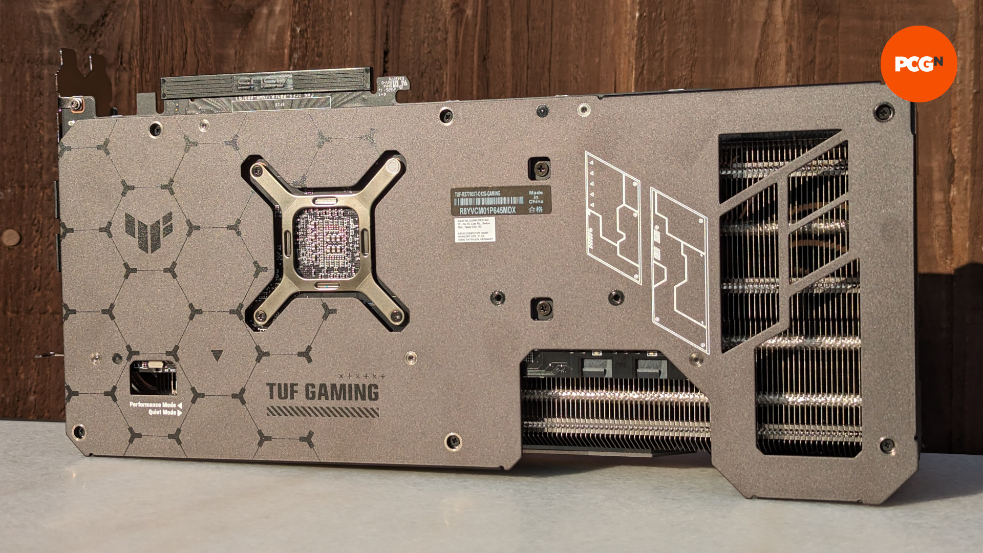 Test de l'AMD Radeon RX 7700 XT : vue arrière du modèle ASUS TUF Gaming de la carte graphique, reposant sur une surface en porcelaine avec un fond en bois