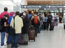 Des gens font la queue avant de passer le contrôle de sécurité à l'aéroport international Pearson de Toronto.