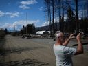 Photo d'archives : Une personne enregistre une vidéo de propriétés détruites par l'incendie de forêt de Bush Creek Est, à Scotch Creek, en Colombie-Britannique, le mercredi 6 septembre 2023.