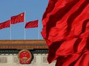 Des drapeaux rouges flottent au vent près de l’emblème national chinois devant le Grand Palais du Peuple à Pékin.