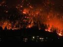 L'incendie de forêt de McDougall Creek brûle à flanc de montagne au-dessus des maisons de West Kelowna, en Colombie-Britannique, le vendredi 18 août 2023.