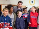 Le capitaine des Canadiens Nick Suzuki pose pour des photos avec des élèves de l'école primaire Maple Grove à Lachine, lundi. 