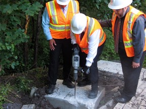 Le maire de Montréal, Denis Coderre, utilise un marteau-piqueur pour détruire les fondations en béton posées pour une boîte postale communautaire.