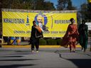 Des femmes passent devant une banderole qui comprend une photographie du défunt président du temple, Hardeep Singh Nijjar, devant le Guru Nanak Sikh Gurdwara Sahib à Surrey, en Colombie-Britannique, le lundi 18 septembre 2023. Le premier ministre Justin Trudeau affirme que les services de renseignement canadiens enquêtent 
