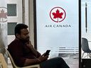 Un homme vérifie son téléphone portable alors qu'il est assis devant un bureau régional d'Air Canada à New Delhi le 20 septembre 2023.