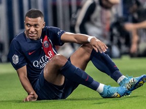 L'attaquant français du Paris Saint-Germain Kylian Mbappe grimace alors qu'il est assis sur le terrain.