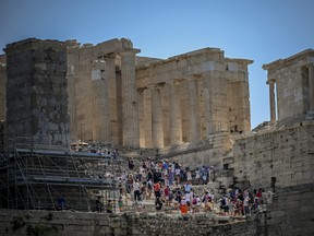 Des touristes visitent le site archéologique de l’ancienne Acropole à Athènes le 13 juillet 2023.