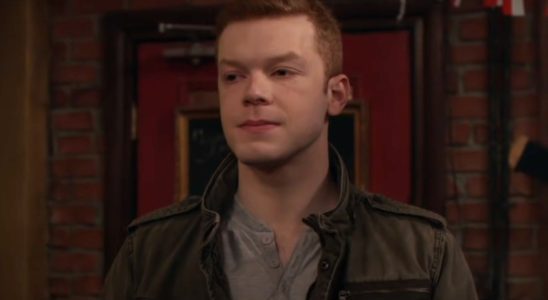 Cameron Monaghan stands in a bar, looking uncertain, in Shameless.