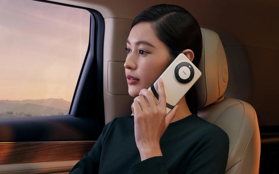 Un mannequin féminin posant avec un Huawei Mate 60 Pro+ dans une voiture de luxe.