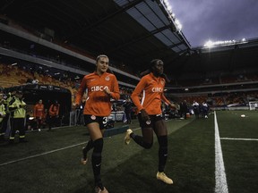 Sydney Collins (à gauche) et Simi Awujo courent sur le terrain du Stade Marie-Marving au Mans, en France, le 11 avril 2023, avant la défaite 2-1 du Canada contre la France lors d'un match amical de football.