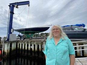 Un plaisancier retire un voilier du quai du port de Chester en prévision de l'arrivée de l'ouragan Lee, alors que Jennifer Chandler, commodore du Chester Yacht Club à Chester, en Nouvelle-Écosse, pose pour une photo, le vendredi 15 septembre 2023.