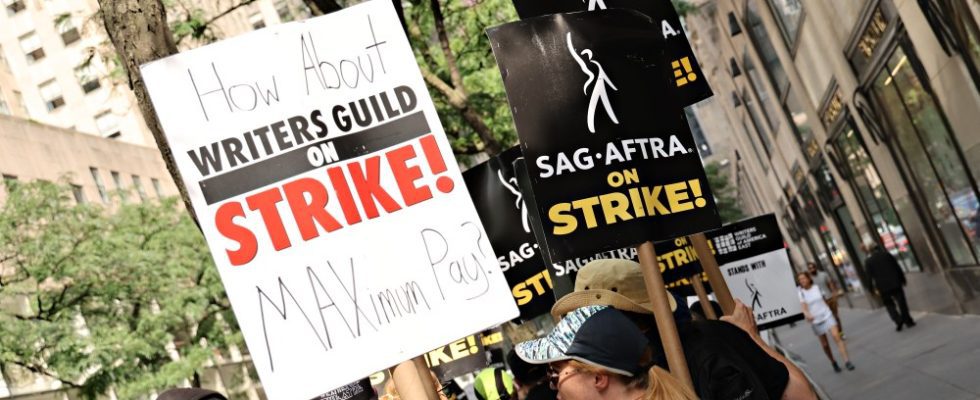 NEW YORK, NEW YORK - JULY 20: Members of the Writers Guild of America and SAG-AFTRA hold up signs outside of 30 Rockefeller Plaza on July 20, 2023 in New York City. Members of SAG-AFTRA, Hollywood's largest union which represents actors and other media professionals, have joined striking WGA (Writers Guild of America) workers in the first joint walkout against the studios since 1960. The strike could shut down Hollywood productions completely with writers in the third month of their strike against the Hollywood studios.  (Photo by Cindy Ord/Getty Images)