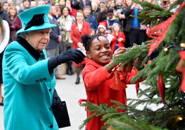 La reine Elizabeth II et Shylah Gordon-Clarke, alors âgées de 8 ans, attachent une boule de Noël à un arbre de Noël lors de sa visite à Coram, la plus ancienne organisation caritative pour enfants du Royaume-Uni.