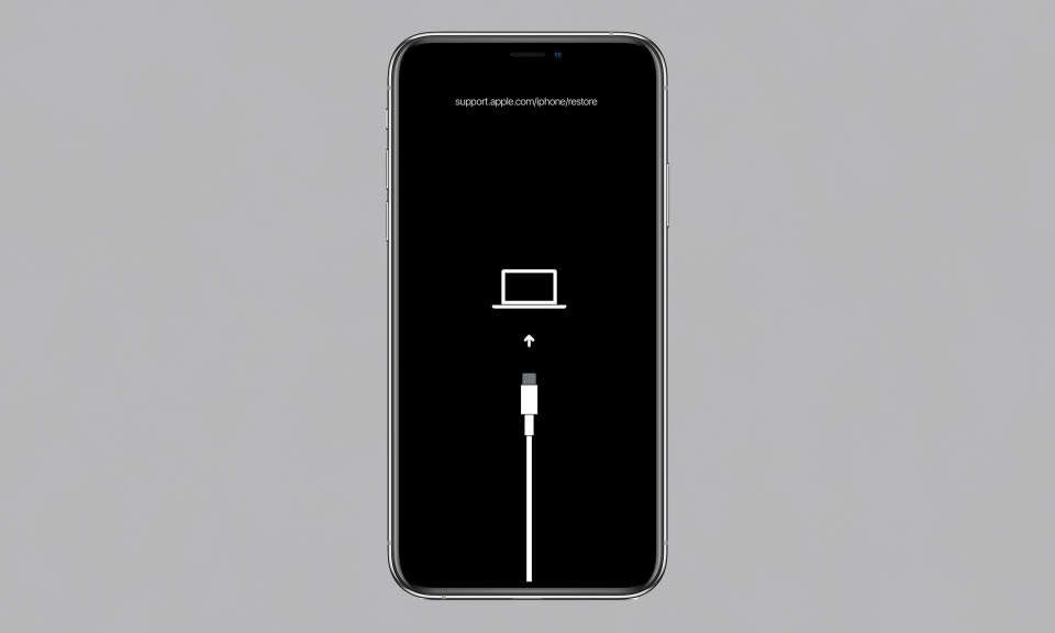 Image d'un iPhone avec un graphique de mode de récupération (câble pointant vers le haut vers un ordinateur portable) sur son écran.  Fond gris.