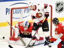 L'attaquant des Sénateurs d'Ottawa Drake Batherson (19 ans) dévie un tir devant le gardien des Panthers de la Floride Spencer Knight lors d'un match de hockey préparatoire de la LNH en troisième période à Sydney, en Nouvelle-Écosse, le dimanche 1er octobre 2023.