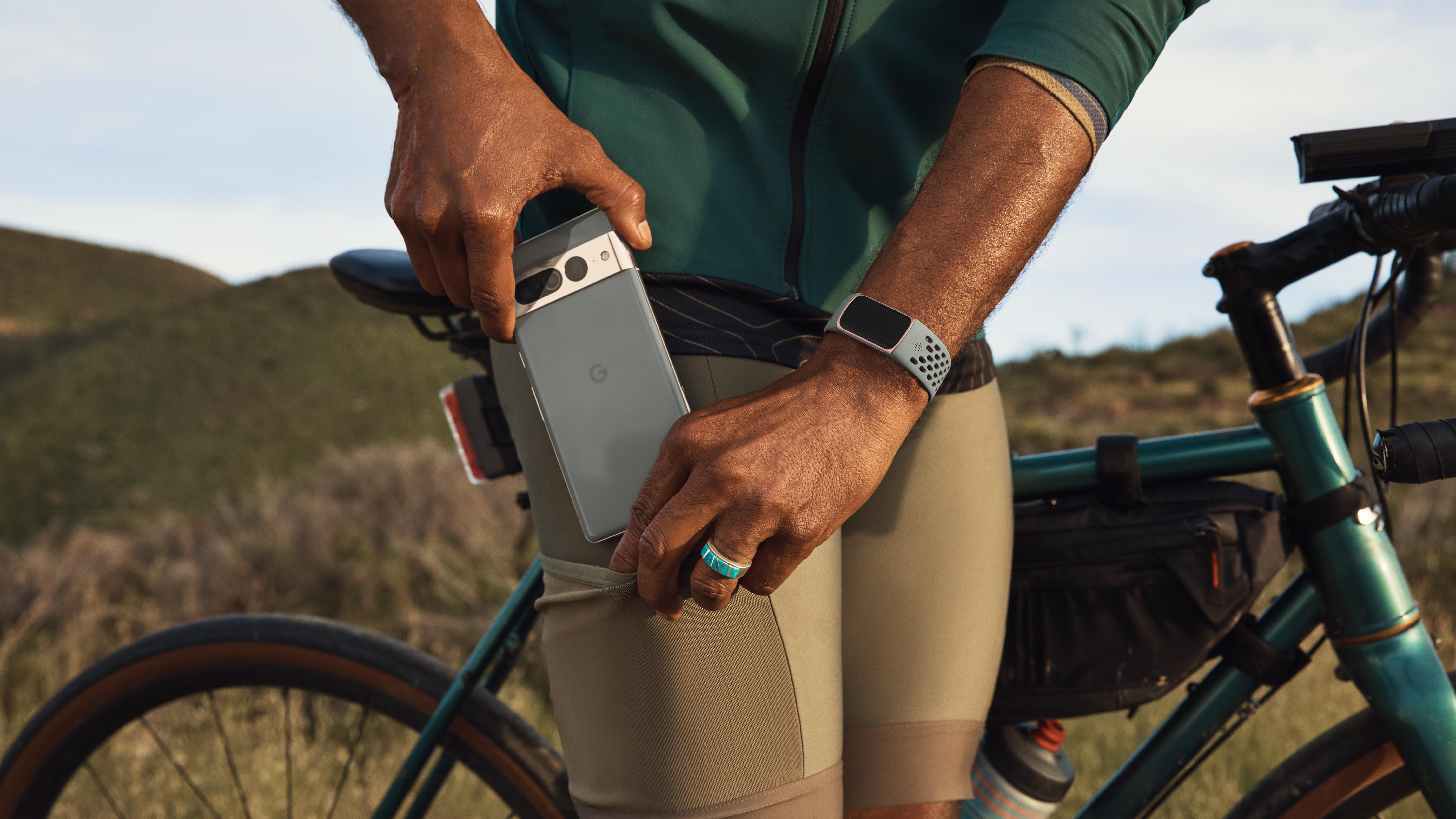 un homme tenant son téléphone Google et portant le Fitbit Charge 6