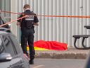 Un policier de Montréal se tient à côté du corps du gangster Francesco Del Balso, tué par balle devant le Monster Gym à Dorval, le lundi 5 juin 2023.