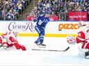 Matthew Knies des Maple Leafs tire sur le gardien des Red Wings de Détroit Alex Lyon alors que Simon Edvinson de Détroit défend lors de l'action préparatoire de deuxième période à Toronto, le jeudi 5 octobre 2023.